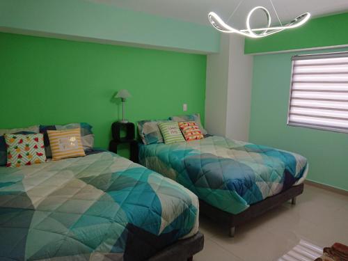 a bedroom with two beds and a green wall at Departamento Centrico Guadalajara in Guadalajara