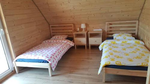 two beds in a room with wooden walls at Eko Przystanek in Kępie Żaleszańskie