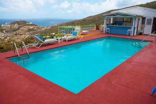 una piscina con 2 sillas y una casa en Villa Fleur De Mer Sint Maarten, en Upper Princeʼs Quarter