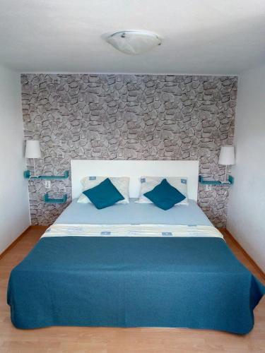 a bedroom with a blue bed with a stone wall at Apartmani Paulo in Vis