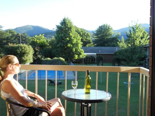 a woman sitting at a table with a bottle of wine at Motel Sierra - Bright in Bright