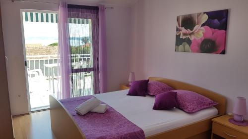 a bedroom with a bed with purple pillows and a window at Apartmani Pavla in Orebić