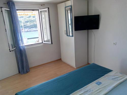 a bedroom with a bed and a flat screen tv at Apartmani Paulo in Vis