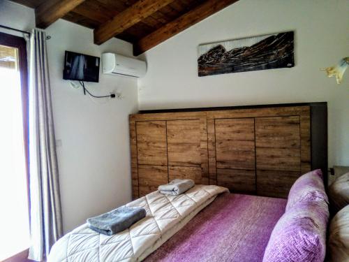 Schlafzimmer mit einem großen Bett mit einem Kopfteil aus Holz in der Unterkunft B&B Stella Maris in Magomadas