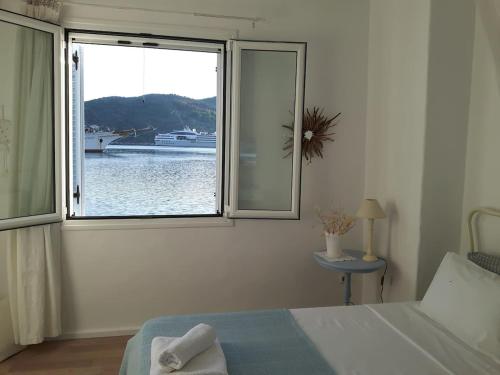 a bedroom with a window with a boat in the water at Cavos Seaside House in Vathi, Ithaka