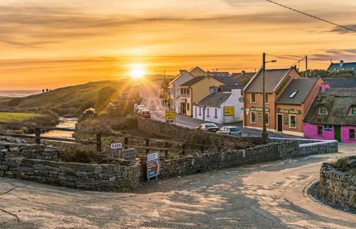 a village with the sun setting on a hill at Boherbui Cottage on the Wild Atlantic Way in Doolin