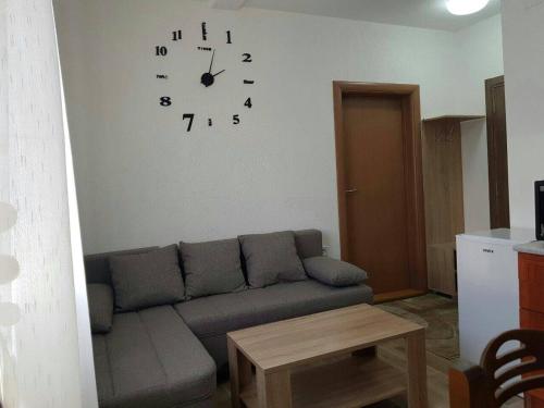 a living room with a couch and a clock on the wall at Apartmani Srećko in Žabljak