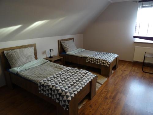 two beds in a room with wooden floors and a window at Cicha 10 Na górze in Ostróda