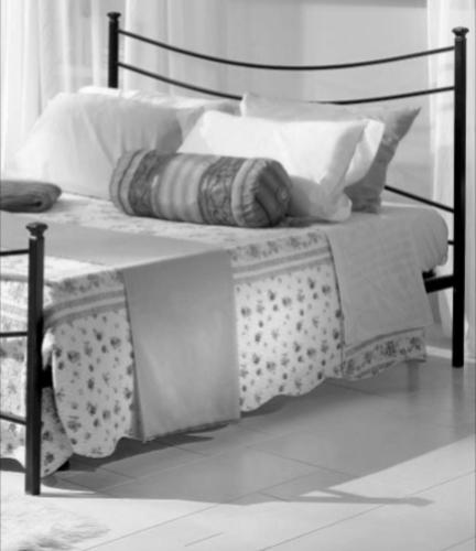 a black and white photo of a bed with pillows at Alessi Suites & Studio in Mazzarino