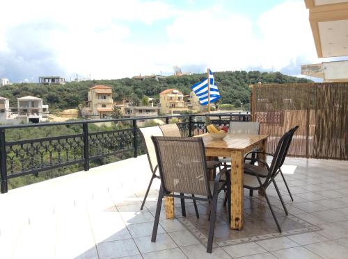 a wooden table with chairs and a flag on a balcony at Anatoli View in Agia Marina Nea Kydonias