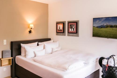 a bedroom with a bed with white sheets and pillows at Staudacherhof in Garmisch-Partenkirchen I Blick aufs Zugspitzmassiv I einzigartige Bayurvida Küche in Garmisch-Partenkirchen