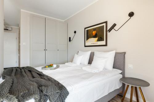1 dormitorio con 1 cama con sábanas blancas y mesa en Happy Stay Old Town Cosy Apt. 367, en Gdansk