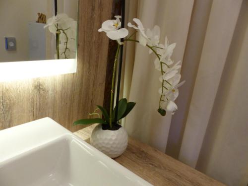 eine weiße Vase mit weißen Blumen auf einem Waschbecken in der Unterkunft Ferienwohnung 14 - Sofia Haus Hühnergott in Ostseebad Sellin