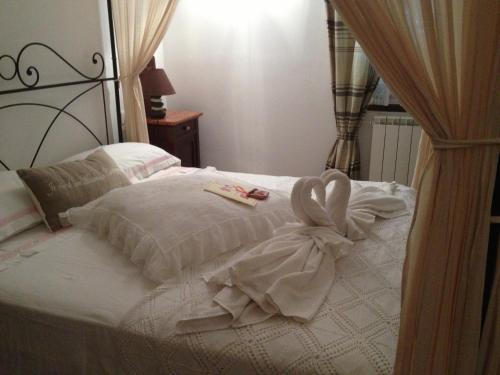 a white bed with a bow on top of it at Le Tartarughe rooms in Magliano in Toscana