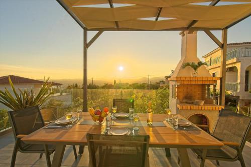 a wooden table and chairs on a patio with a fireplace at Vista Blu Villa in Vlachata