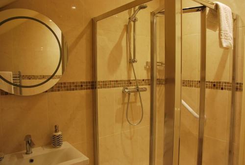 a bathroom with a shower and a sink and a mirror at Teach Cruachan Bed and Breakfast in Dooagh