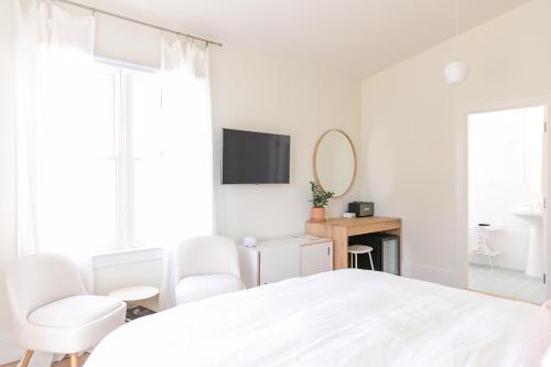a white bedroom with a white bed and two chairs at Guest House Raleigh- Adults Only in Raleigh