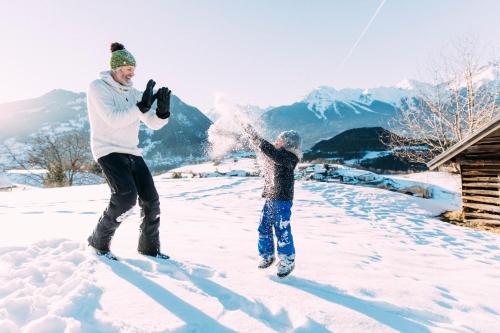 a man and a child playing in the snow at Pitzis Kinderhotel - Family Only in Arzl im Pitztal
