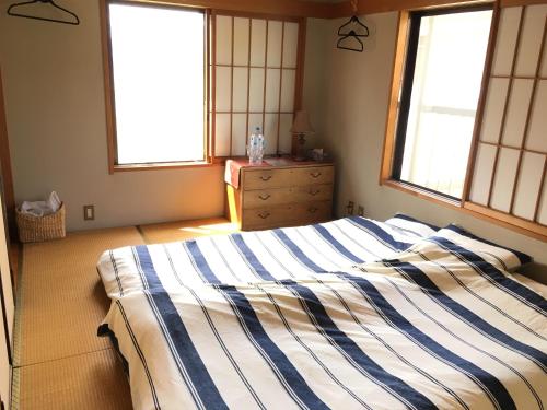 a bedroom with two beds and a dresser and two windows at Koto House in Yachiyo