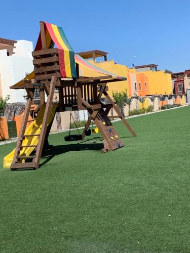 a wooden playground with a slide on the grass at La Casa de Los Milagros in San Miguel de Allende
