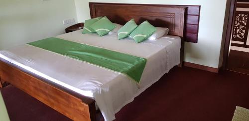 a bedroom with a bed with green and white pillows at Acquabey Surf Villa in Matara