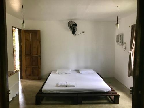 a bedroom with a bed with white sheets and a door at The Broken Board in General Luna