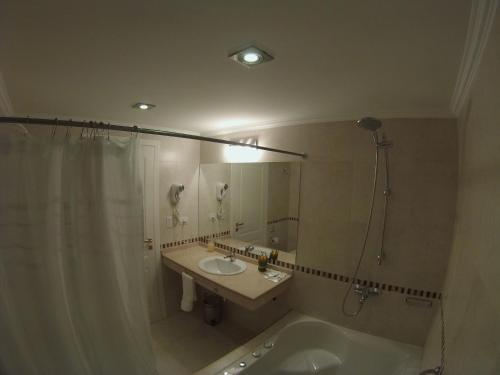 y baño con bañera, lavamanos y ducha. en Alma Andina Hosteria, en Villa La Angostura