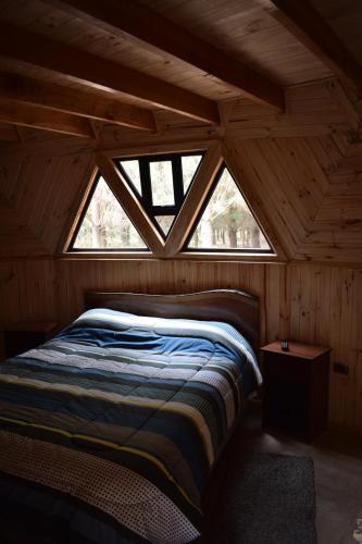 uma cama num quarto de madeira com uma janela em Domos Nelkewue em Santa Bárbara