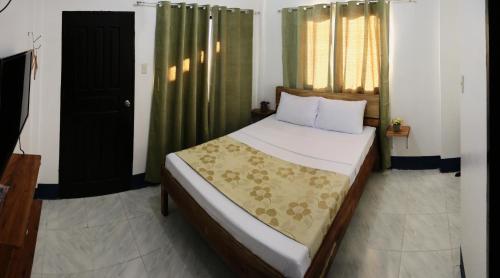 Schlafzimmer mit einem großen Bett und grünen Vorhängen in der Unterkunft Keen's Place in Puerto Princesa