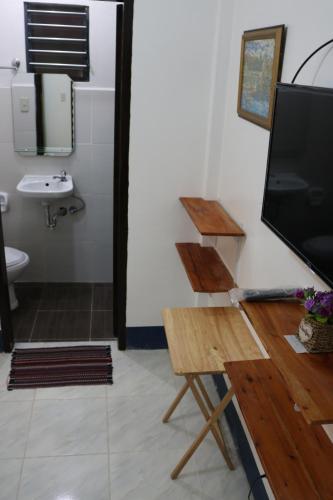 a bathroom with a tv and a toilet and a sink at Keen's Place in Puerto Princesa City