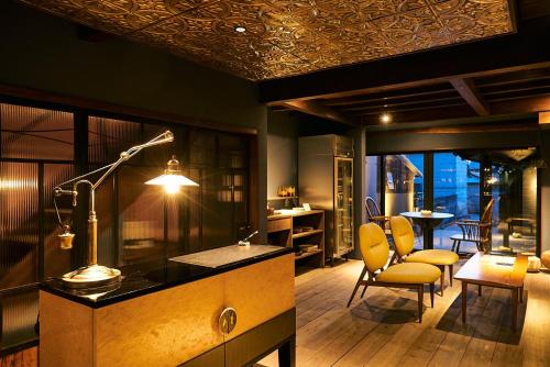 a room with a desk with a lamp and chairs at Bed and Craft in Nanto