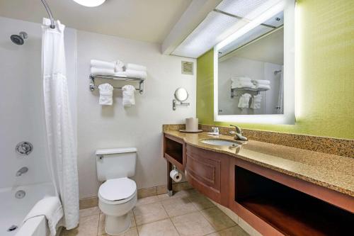 a bathroom with a toilet and a sink and a mirror at Comfort Inn Anaheim Resort in Anaheim