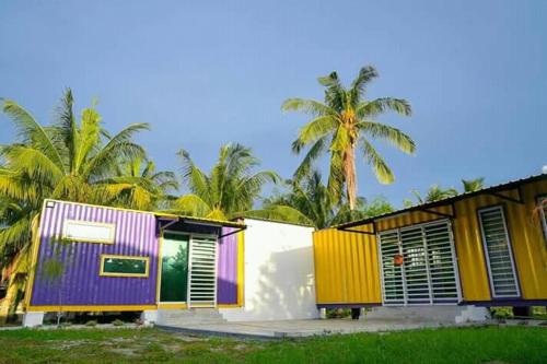a house with colorful doors and palm trees at Yellow Cube at Lumut Cube Homestay Kontena in Lumut