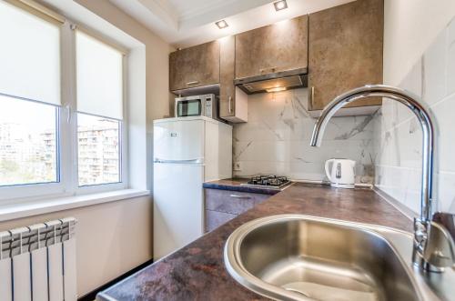 a kitchen with a sink and a white refrigerator at ARTAL Apartment on Obolonsky avenue 16a in Kyiv