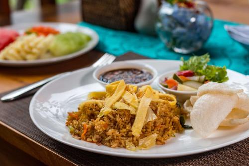 a plate of food with rice and chips on a table at The Pesaren Ubud in Ubud