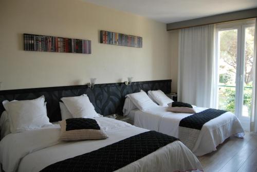 a room with three beds with white sheets at Logis Hôtel Restaurant Les Aubuns in Caissargues