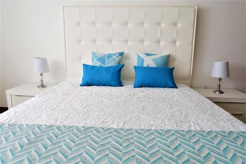 een slaapkamer met een groot bed met blauwe kussens bij Estrelinha GuestHouse in Nazaré