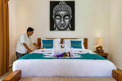 a man is standing next to a bed with a statue at The Pesaren Ubud in Ubud