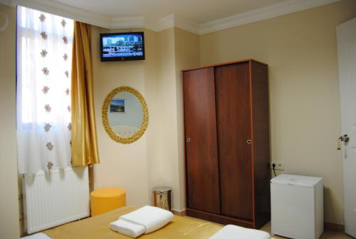 a bedroom with a wooden cabinet and a television on the wall at Lotus Hotel in Istanbul