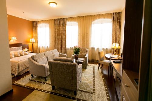 a hotel room with a bed and a couch and chairs at AllureInn Hotel and Spa in Chernivtsi