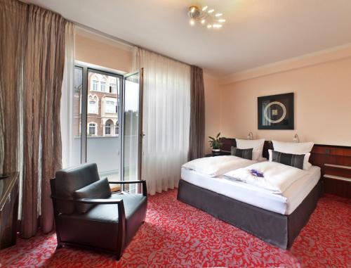 a hotel room with a bed and a chair at Top Hotel Krämer in Koblenz