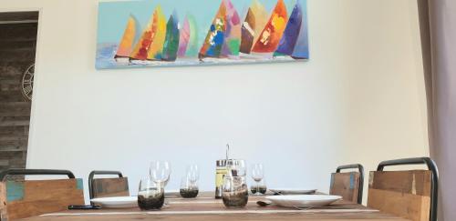 - une table avec des verres à vin et une peinture sur un voilier dans l'établissement Appartement Le Flobart - 50M plage - Terrasse, à Berck-sur-Mer