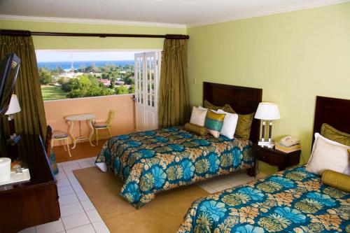 a hotel room with two beds and a balcony at Cardiff Hotel and Spa in Runaway Bay