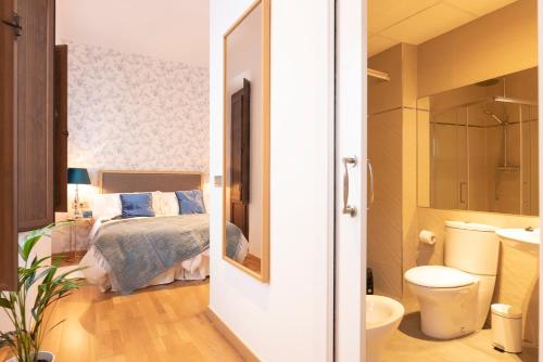 Un dormitorio con una cama y un baño con inodoro. en San Jerónimo 17 Suites, en Granada