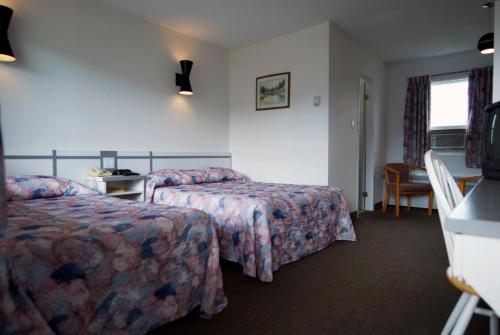 a hotel room with two beds and a television at Daigle's Motel in Saint Leonard