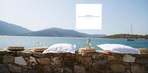 a stone wall with pillows on it next to the water at blueline guesthouse in Áyios Dhimítrios