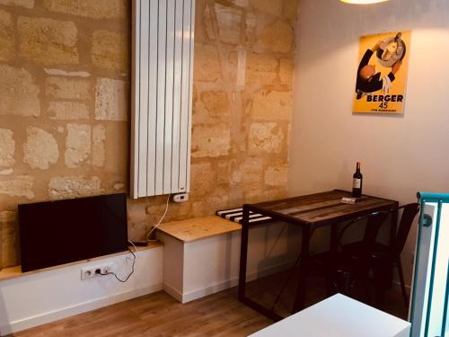 un salon avec une table et une télévision dans l'établissement Les Suites de La Villa Mouneyra, à Bordeaux
