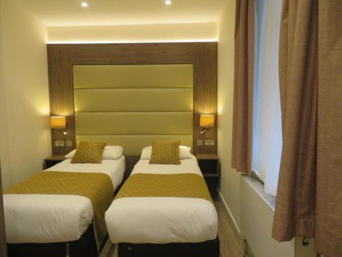 een kamer met drie bedden in een kamer bij Glendale Hyde Park Hotel in Londen