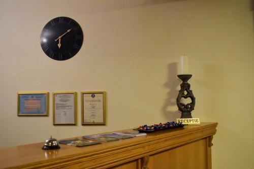 a clock on a wall with a candle on a cabinet at Vila Seva in Vatra Dornei