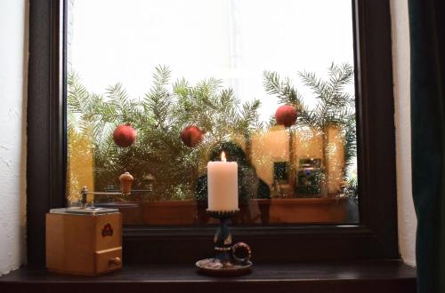 a candle in front of a window with christmas trees at Vila Seva in Vatra Dornei